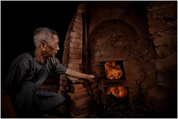 Xiong Zhonggui tending the wood fire during dragon-kiln firing